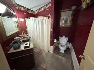 Bathroom featuring a shower with shower curtain, vanity, radiator heating unit, vaulted ceiling, and dark tile patterned floors