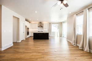 Kitchen featuring white cabinetry, light countertops, ceiling fan, a kitchen island with sink, and dark wood-type flooring