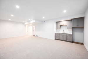 Below grade area featuring light carpet, recessed lighting, and wet bar