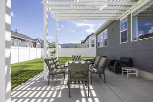 Fenced backyard featuring outdoor dining area, a patio, a pergola, and a mountain view