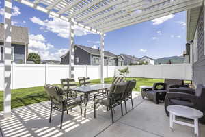 Fenced backyard with a patio, outdoor dining area, a residential view, and a pergola
