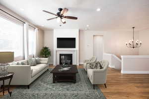 Living area with wood finished floors, suspended lighting, ceiling fan, and a glass covered fireplace