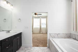 Full bathroom with vanity, a bath, light marble finish floors, and ceiling fan