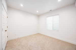 Empty room with recessed lighting and light colored carpet