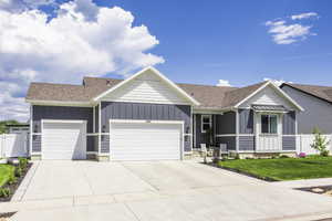 Single story home featuring board and batten siding, a shingled roof, a garage, and driveway