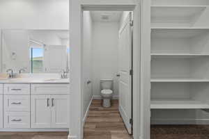 Bathroom featuring double vanity, a closet, and light wood-style flooring