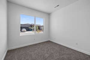 Unfurnished room featuring baseboards and dark colored carpet
