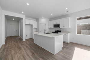 Kitchen with white cabinetry, stainless steel appliances, a kitchen island with sink, light wood-style flooring, and recessed lighting
