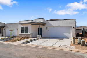 Contemporary home with a garage, concrete driveway, stucco siding, and stone siding
