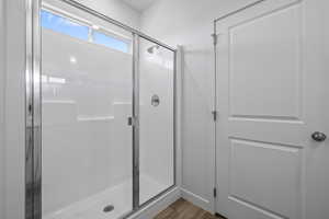 Full bathroom featuring a shower stall and dark wood finished floors