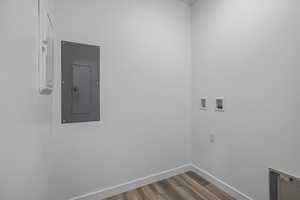 Laundry area featuring electric panel, hookup for a washing machine, and wood finished floors