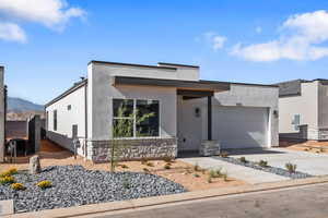 Contemporary home with a garage, concrete driveway, stucco siding, and a mountain view