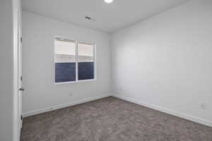 Spare room featuring baseboards and dark colored carpet