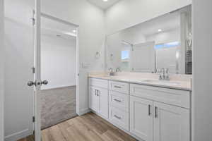 Bathroom featuring double vanity, light wood-style floors, and recessed lighting