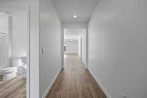 Hall with wood finished floors and recessed lighting