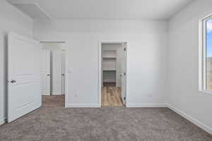 Unfurnished bedroom with a walk in closet and light carpet