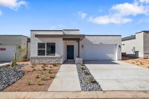 Contemporary home with an attached garage, concrete driveway, stucco siding, and stone siding