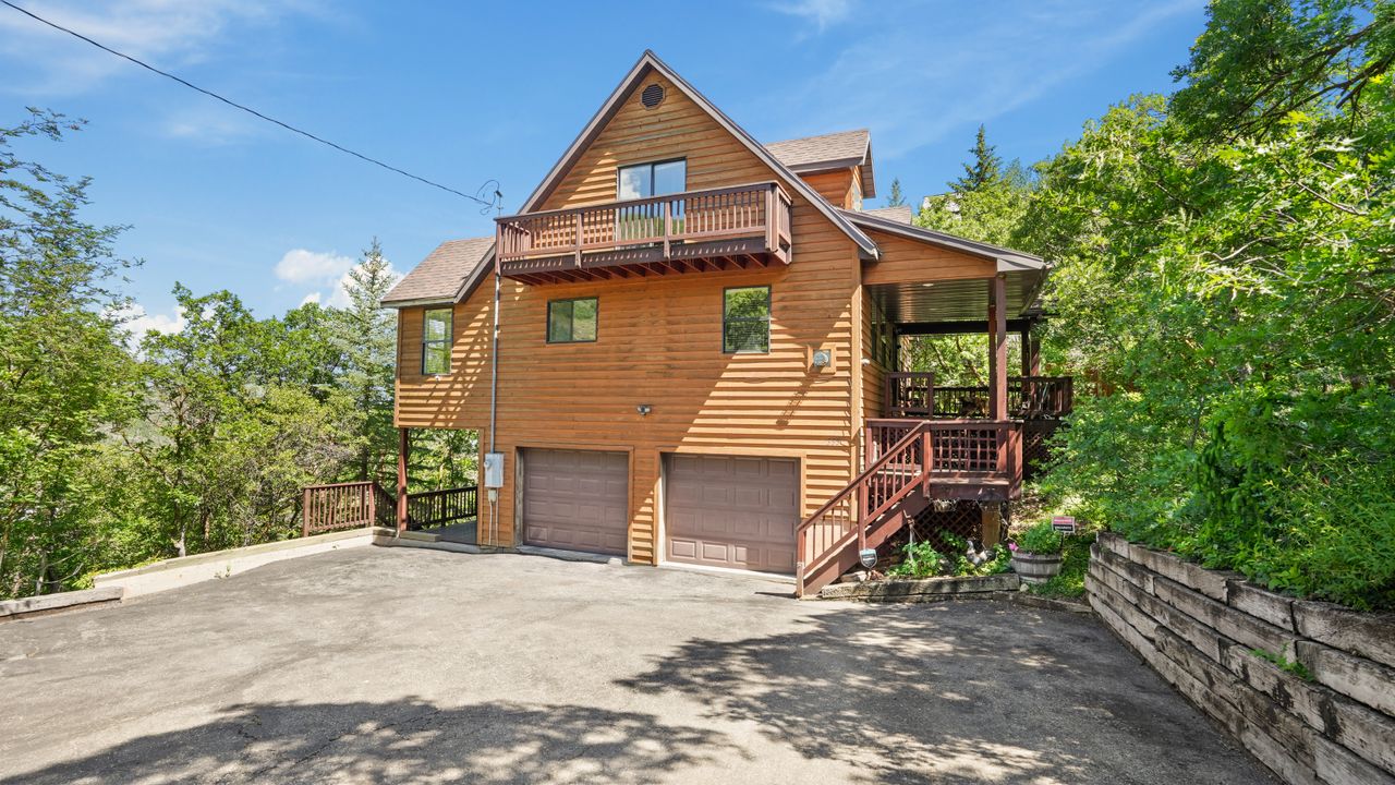 View of front of home featuring driveway, a garage, and a balcony