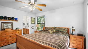 Bedroom with light colored carpet, connected bathroom, and a ceiling fan