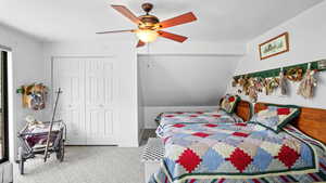 Bedroom with light colored carpet, ceiling fan, a closet, and vaulted ceiling