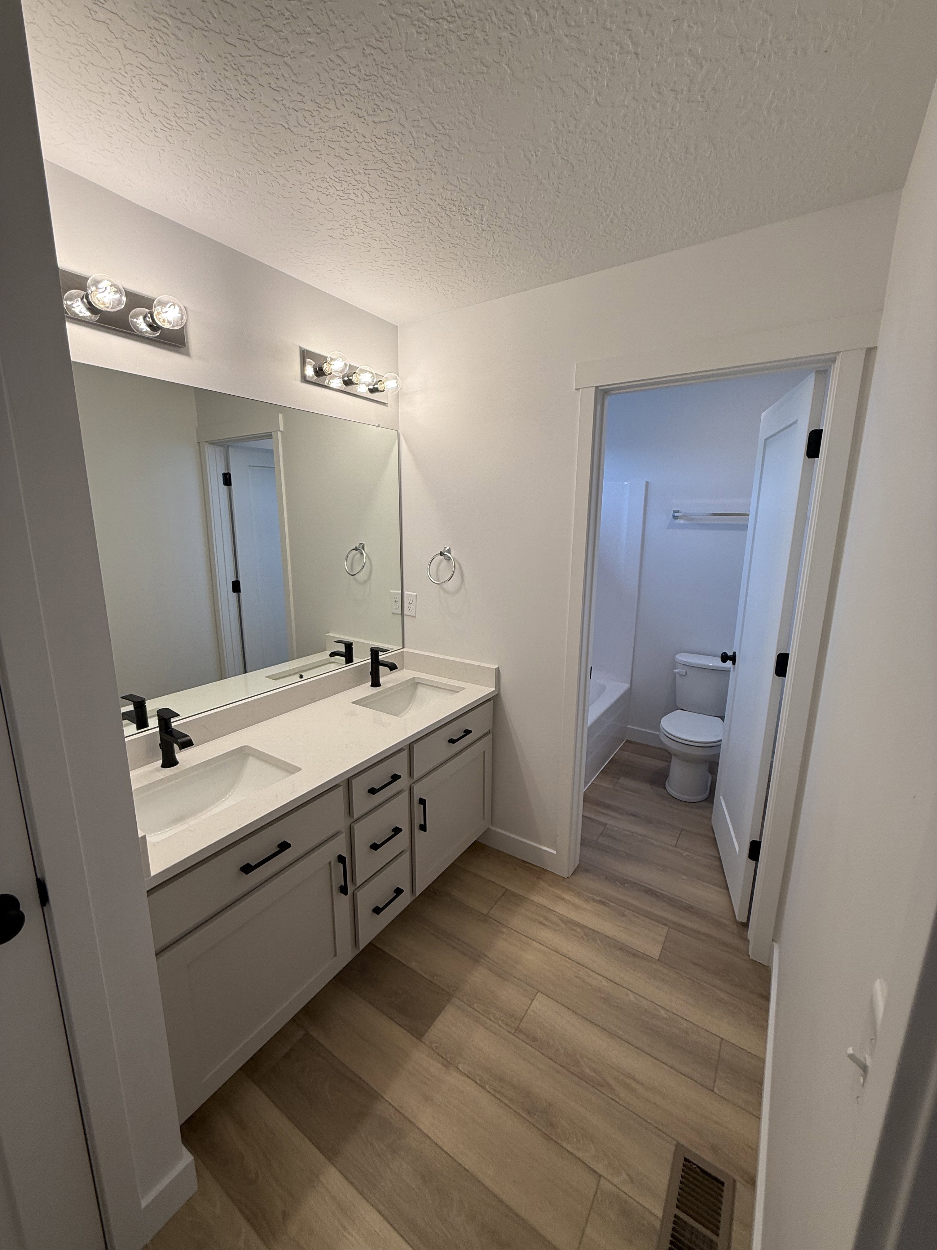 Double vanity featuring light-colored cabinetry, integrated sinks, black fixtures, and a large mirror