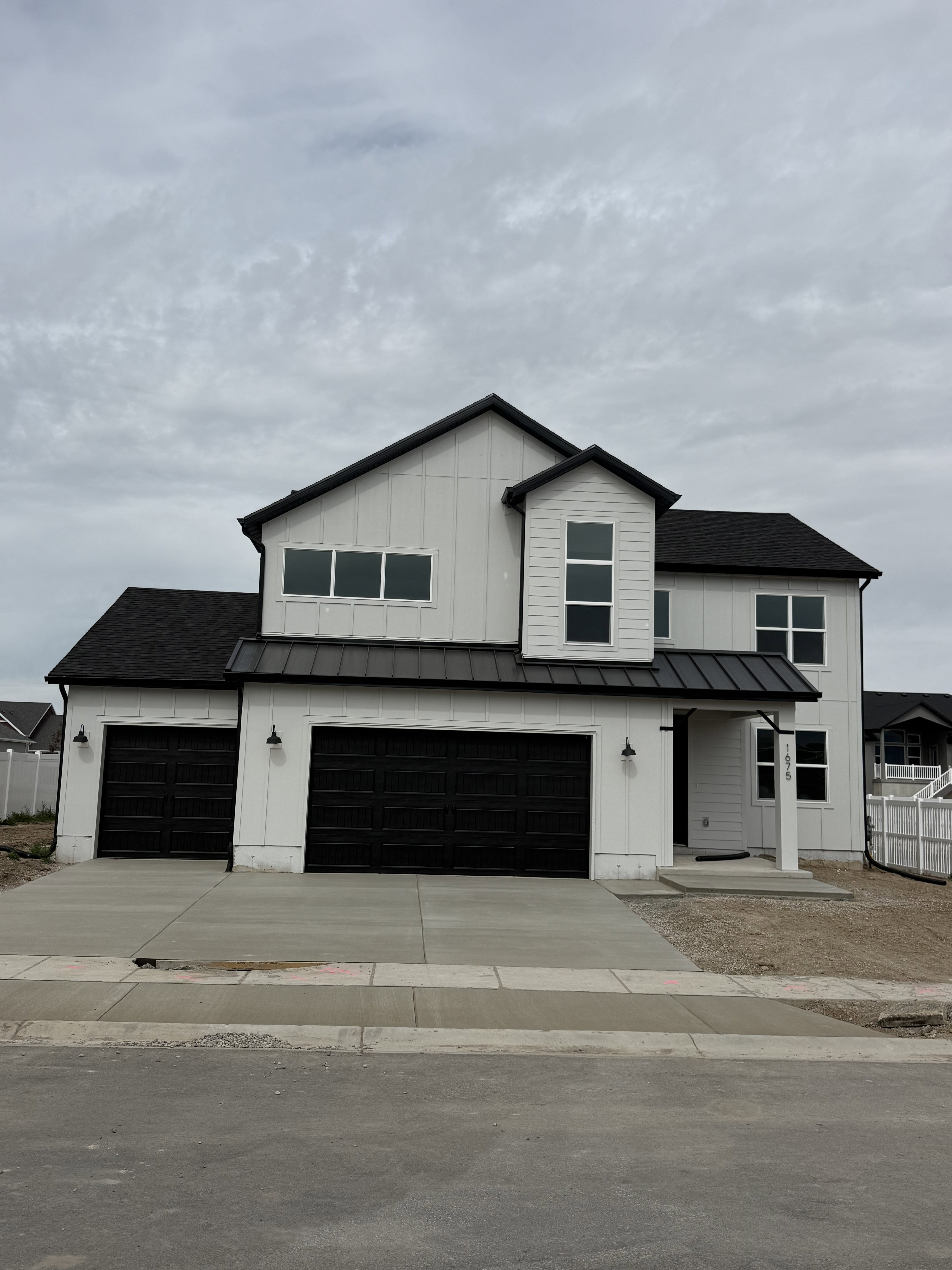 Contemporary two-story residence featuring white vertical siding with dark trim accents