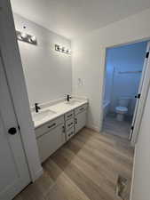 Bathroom featuring double vanity, light wood-style floors, and a textured ceiling