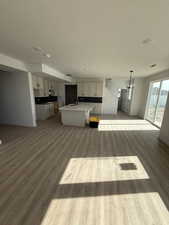 Unfurnished living room with light wood-type flooring, a textured ceiling, and hanging lights