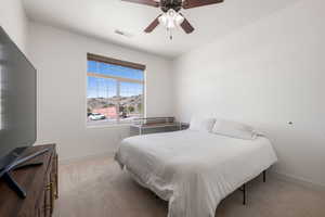 Bedroom with light carpet, ceiling fan, and a mountain view