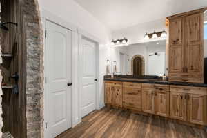 Full bath with double vanity and dark wood-type flooring
