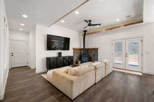 Living area with a ceiling fan, dark wood finished floors, recessed lighting, a wood stove, and french doors