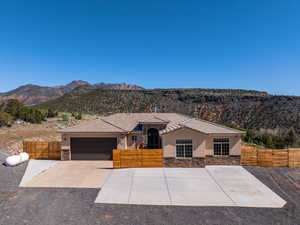 View of front of property featuring a fenced front yard, stone siding, stucco siding, and an attached garage