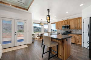 Kitchen with dark countertops, a center island with sink, french doors, and a breakfast bar