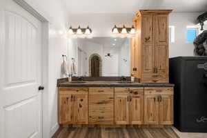 Full bath with double vanity and dark wood-type flooring