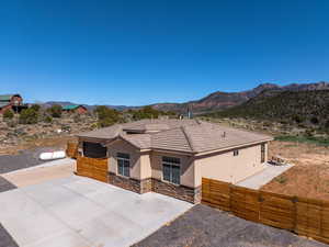Single story home featuring a gate, a mountain view, stucco siding, stone siding, and a tiled roof