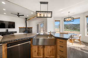 Kitchen featuring dishwashing machine, light wood finished floors, a wood stove, open floor plan, and wood finish cabinetry