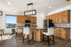 Kitchen featuring an island with sink, a breakfast bar, and dark wood-style flooring