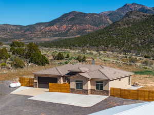 View of front of property featuring stone siding, a mountain view, an attached garage, stucco siding, and driveway