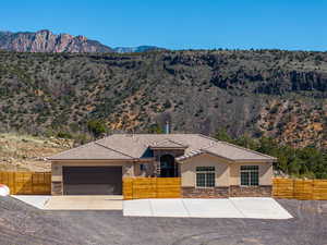 View of front of house featuring a fenced front yard, stone siding, a mountain view, and stucco siding