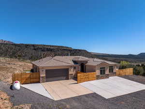 View of front of property with stone siding, a mountain view, an attached garage, stucco siding, and a tile roof