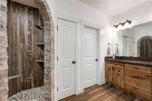 Bathroom with vanity, a walk in shower, and dark wood-style floors