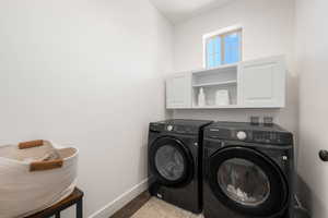 Laundry area featuring washer and clothes dryer, light wood-style flooring, and cabinet space