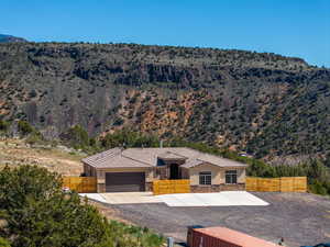 View of front of house featuring stucco siding, a garage, stone siding, concrete driveway, and a mountain view