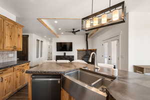 Kitchen featuring open floor plan, dishwashing machine, a wood stove, a ceiling fan, and backsplash
