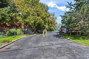 View of asphalt road featuring curbs and a gated entry