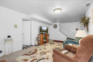 Carpeted living room featuring stairway and a textured ceiling
