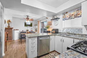 Kitchen featuring a peninsula, black gas range, stainless steel dishwasher, light wood-style floors, and a ceiling fan