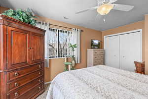 Bedroom with ceiling fan, a closet, and carpet flooring