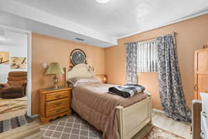 Bedroom with light wood finished floors and a textured ceiling