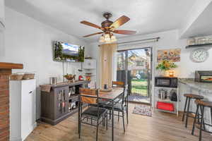 Dining room featuring light wood finished floors, a ceiling fan, and a textured ceiling